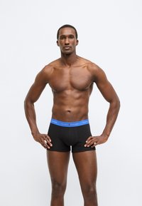 Mustad bokserid sinise elastse vöökohaga, millel on "TOMMY HILFIGER" logo. Sile tekstuur, keha järgnev lõige ja keskmise reie pikkus.