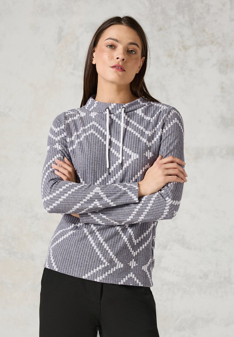 Pullover mit Kapuze aus grauem Stoff, der ein weißes geometrisches Muster aufweist. Lange Ärmel mit tailliertem Schnitt und leichtem Material.