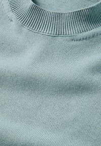 Helle blaue Strickpullover-Textur mit einem gerippten Rundhalsausschnitt, der eine glatte Oberfläche und gleichmäßige Nähte aufweist.