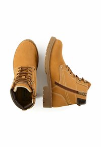 Beżowe skórzane buty o wytrzymałym designie, z metalowymi oczkami i zamkiem błyskawicznym z boku. Charakteryzują się wyraźnym przeszyciem i teksturowaną gumową podeszwą.