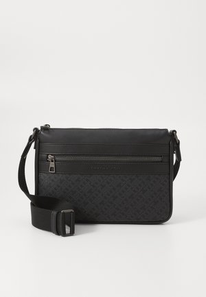 Sac bandoulière noir avec sangle réglable, poche zippée frontale et motif subtil avec le logo Tommy Hilfiger sur un matériau texturé.