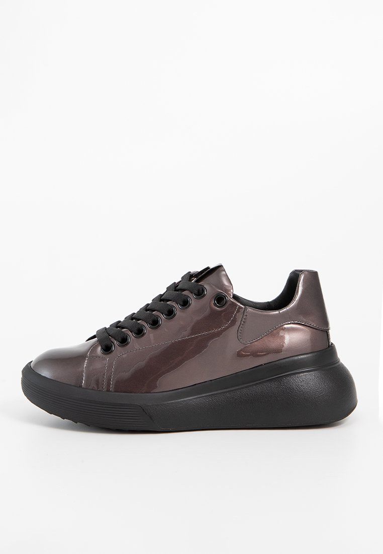 Eleganter grauer Sneaker mit glänzendem Obermaterial, schwarzen Schnürsenkeln, runder Zehenpartie und einer klobigen schwarzen Sohle, die glatte Texturen und minimale Akzente aufweist.