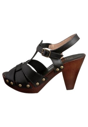 Sandale à talons en cuir noir au design à lanières, dotée de clous décoratifs en or et d'un talon en bois. Avec une bride de cheville ajustable.