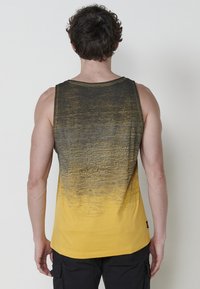 Rumena in črna gradient majica brez rokavov z sproščenim krojem, okroglo izrezom in vidnimi šivi. Mekan teksturiran material.