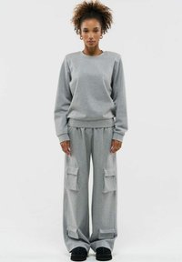 Grijze sweatshirt en bijpassende wide-leg cargobroek met grote zakken, gemaakt van zacht materiaal; voorzien van ribbelboorden en een elastische tailleband.