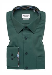 Groene blouse met knopen, voorzien van een visgraatstructuur, moderne pasvorm, contrasterend geruit patroon in de kraag en mouwen, en zwarte knopen.