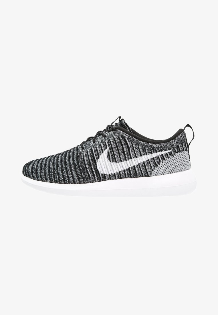 Černé a šedé pletené běžecké tenisky Nike s bílým logem swoosh a bílou podrážkou, pohled ze strany.