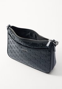 Borsa a mano in pelle nera con motivo in logo stampato, chiusura con zip, accessori in argento e una singola tracolla regolabile. L'interno è foderato e spazioso.