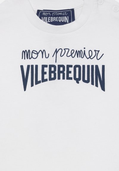 Fehér anyag tengerészkék felirattal: „mon premier VILEBREQUIN”, valamint hozzáillő márkajelzéssel az újszülött ruházat nyakánál.