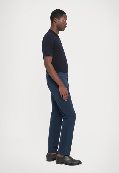 Navy blue trousers with a tailored fit, made of cotton blend fabric. Smooth texture, side pockets, and black leather shoes.