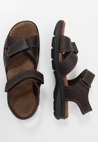 Sandali in pelle marrone con cinturini regolabili, suole imbottite e suole in gomma testurizzata. Cuciture rinforzate e design open-toe.