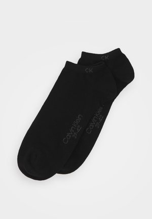 Black ankle socks made of soft fabric, featuring a seamless design, with printed "Calvin Klein" branding and size details on the side.