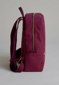 Mochila malva de forma rectangular, con tejido texturizado, un cierre dorado y correas ajustables. Presenta un bolsillo lateral para almacenamiento adicional.