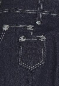 Tummansininen denimi, jossa on takatasku, jossa on kuluneet yksityiskohdat ja valkoinen ommel. Esittelee voimakkaan vyötärönauhan ja klassisen muodon.