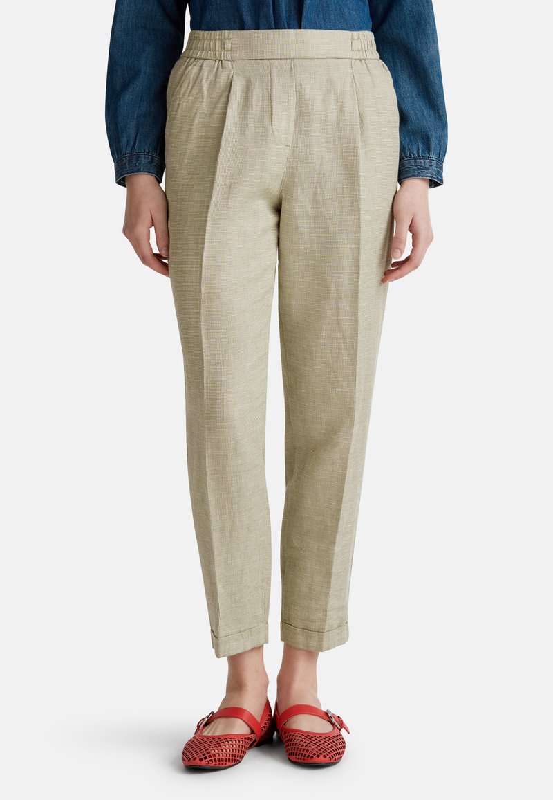 Pantalons à carreaux beige clair avec une coupe fuselée, dotés d'un devant plissé et d'une taille élastique, associés à des chaussures plates rouges.