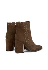 Botas de tobillo de ante marrón con punta afilada, talón grueso con detalles dorados y tachuelas metálicas a lo largo de los costados. Cierre de cremallera en la parte trasera.