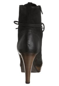 Botas de cuero negras hasta el tobillo con un alto tacón de madera, con cierre de cremallera y cordones decorativos en la parte trasera, textura suave y forma estilizada.