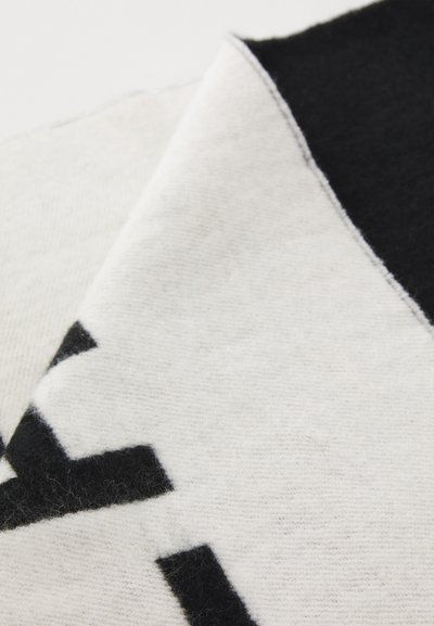 Wool blend scarf featuring a black and white geometric pattern, soft texture, and a folded edge detailing.