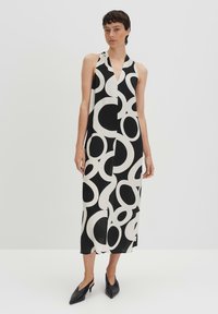 Halterneck-Kleid in Schwarz und Creme, mit einem geometrischen Kreisdesign. Hergestellt aus einem glatten Stoff mit einem fließenden, knielangen Schnitt.