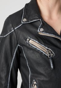 Black leather jacket with silver zippers and hardware. Features contrast stitching and a slightly structured collar.
