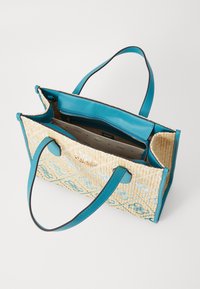 Woven straw tote bag with turquoise synthetic leather handles and trim, featuring an interior pocket and a floral pattern on the exterior.
