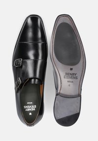 Zwarte leren dubbele monk strap schoenen met een slank ontwerp. Voorzien van zilverkleurige gespen, gesloten neus en een contrasterende bruine leren binnenzool.