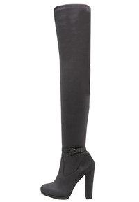 Botas de gamuza negra hasta la rodilla con suela de plataforma y un tacón alto y cuadrado. Presentan un detalle de hebilla en el tobillo. Textura suave en toda su superficie.