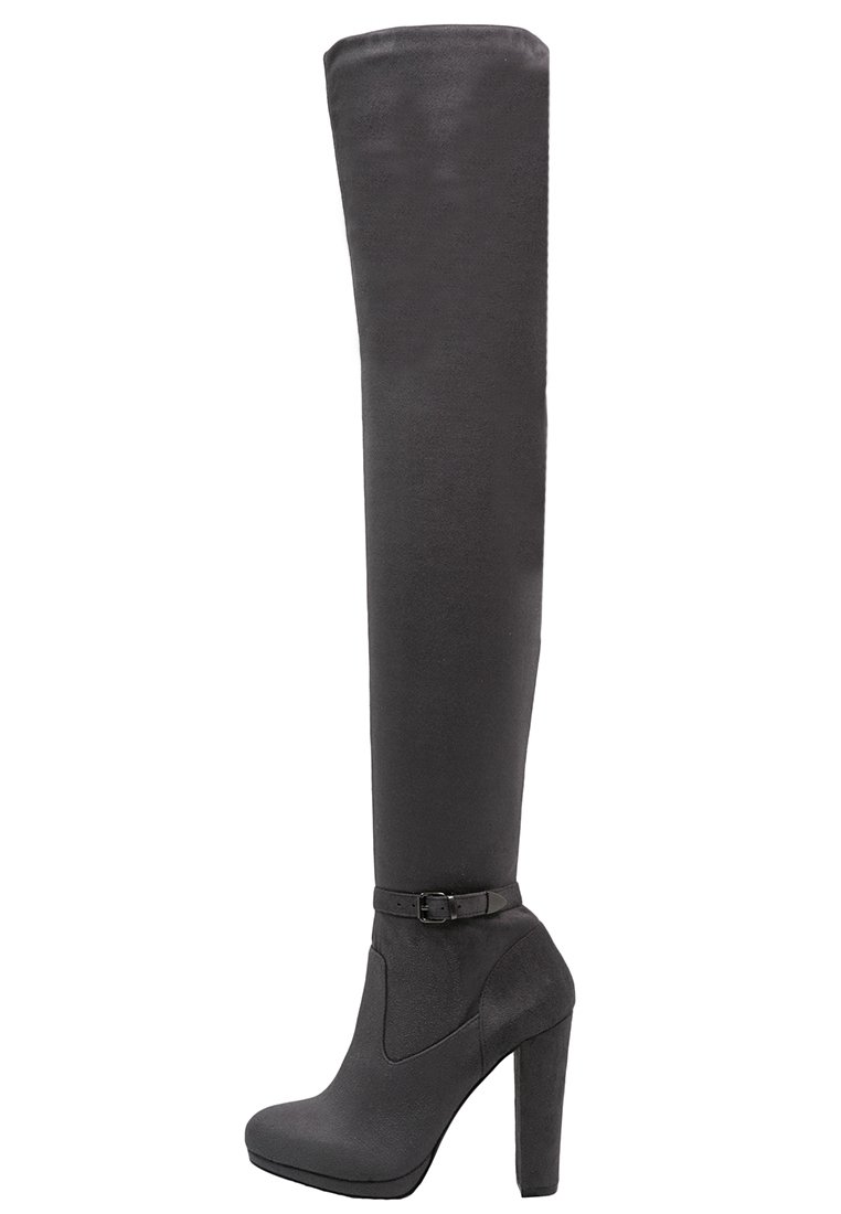 Botas de gamuza negra hasta la rodilla con suela de plataforma y un tacón alto y cuadrado. Presentan un detalle de hebilla en el tobillo. Textura suave en toda su superficie.