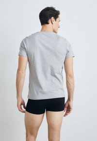 T-shirt en coton gris et boxers noirs, manches courtes, design ajusté, texture lisse, vu de derrière.