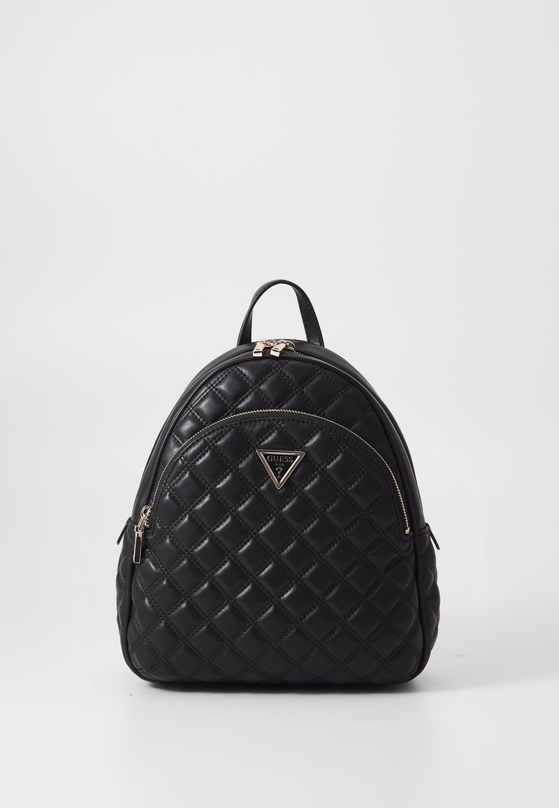 Petit sac à dos noir matelassé avec poche avant zippée et logo argenté Guess sur fond blanc épuré.