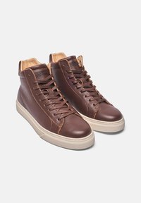Braune Leder High-Top Sneaker mit strukturierter Oberfläche, runder Zehenpartie, kontrastierenden hellbraunen Akzenten und cremefarbenen Gummisohlen.