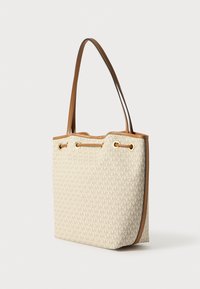 Tassen in beige canvas met een repetitief logo-patroon, voorzien van bruine leren accenten, oogjes en een ontwerp met dubbele handvatten.