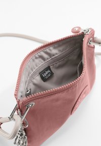 Kompakt rosa nylonväska med grå insida, dragkedjeslutning och kedjedetaljer. Har en logopatch och texturerad dragkedjeskons.