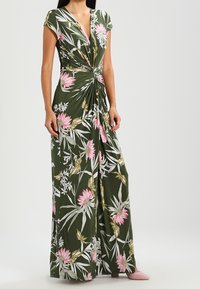 Abito maxi floreale verde con stampa di fiori rosa e bianchi. Presenta maniche corte a cappuccio e un dettaglio frontale torcigliato. Tessuto morbido.