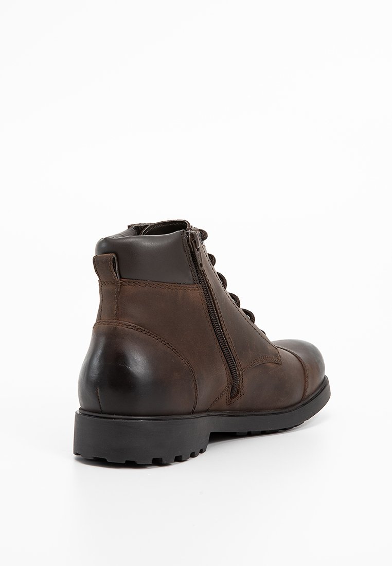 Brązowe skórzane botki do kostki z zaokrąglonym noskiem, bocznym zamkiem błyskawicznym i grubą gumową podeszwą. Posiadają sznurowane przody i gładką fakturę.