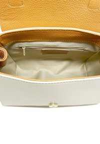 Bolso de cuero con un exterior crema y un interior marrón claro. Cuenta con un bolsillo con cremallera y un cierre magnético. Superficie texturizada.