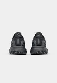 Black athletic shoes featuring a mesh upper, padded collar, textured outsole, and subtle branding on the heel and sides.