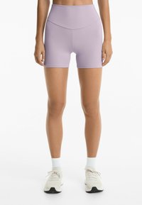 Lilac shortsit, joissa on korkea vyötärö ja jotka on valmistettu sileästä, venyvästä materiaalista. Niissä on tiukka malli ja ne ulottuvat reiden keskikohtaan.