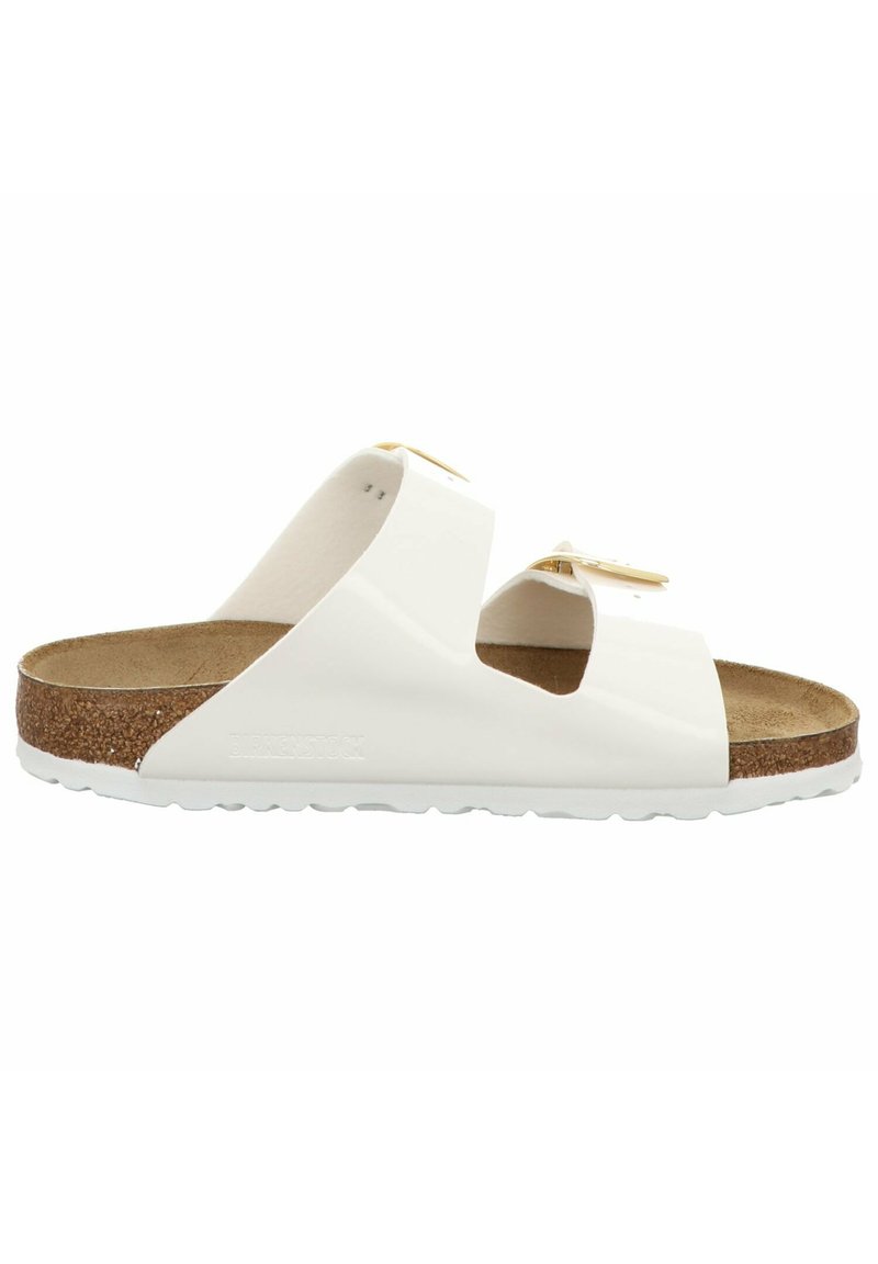 White slide sandals with two wide straps, cork footbed, textured outsole, and subtle gold hardware accents. Flat design with open toe.