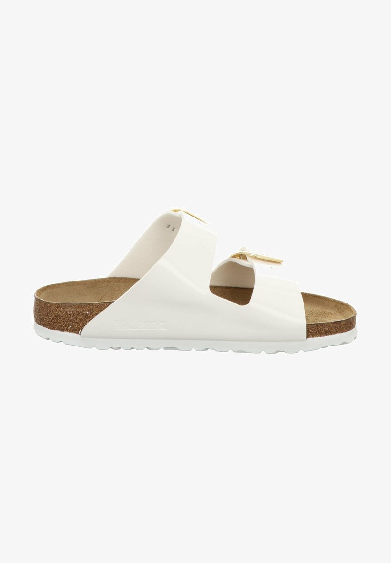 White slide sandals with two wide straps, cork footbed, textured outsole, and subtle gold hardware accents. Flat design with open toe.