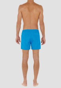 Modré plavky vyrobené z lehkého materiálu, s elastickým pasem a zadní kapsou. Hladká textura, délka nad kolena.
