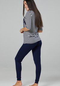 Striped navy and white top with three-quarter sleeves paired with solid navy leggings. Soft, lightweight fabric with a relaxed fit.