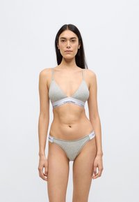 Γκρι βαμβακερό μπραλέτο με λεπτές τιράντες και τριγωνικό σχήμα, σετ με αντίστοιχο γκρι σλιπ που διαθέτει λευκή ταινία Calvin Klein.