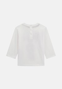 Weißes Langarmshirt mit Rundhalsausschnitt. Mit einem Knopfverschluss auf der Rückseite und einer glatten, weichen Textur.