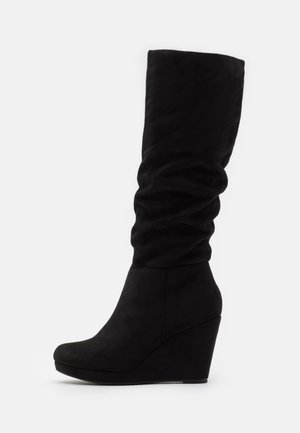 Schwarze Wildleder-Knöchelhohe Wedge-Stiefel mit einer lässigen oberen Partie, runder Zehenpartie und glatter Textur. Der Keilabsatz sorgt für Höhe und Stabilität.