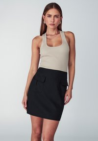Top a maniche larghe a righe beige abbinato a una gonna nera aderente con due tasche anteriori. Tessuto dalla trama liscia, design minimalista.