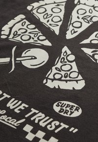 Tela negra con un gráfico blanco de porciones de pizza dispuestas en un círculo y un cortador de pizza, con el texto "SUPER DRY" y un eslogan parcial abajo.