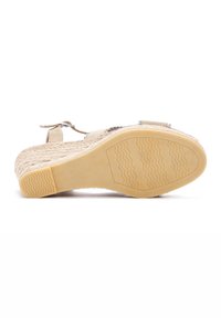 Beige sandaal met een textuur bovenwerk, verstelbare riem en een rubberen zool met een golvend looppatroon.
