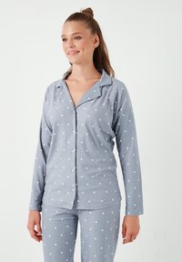 Ensemble de pyjama gris clair en tissu doux, orné de pois blancs. Le haut présente un col à revers et une fermeture à boutons, avec des manches longues, et un pantalon assorti.