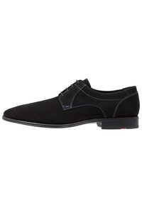 Chaussure noire en suède à lacets avec un profil bas, présentant des coutures contrastantes et une semelle lisse. Design simple avec un bout arrondi.